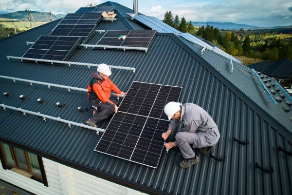 Zwei Männer bauen auf einem Dach Solaranlagen auf